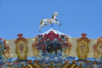 Colourfully decorated carousel with horse decoration under a clear blue sky, summer,