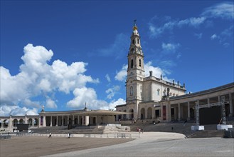 Spacious square with an imposing bell tower and surrounding colonnades under a blue sky, Basilica