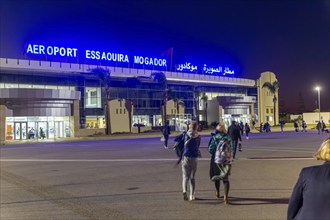 Passengers walking to airport terminal building at night, Aeroport Essaouira Mogador, Morocco,