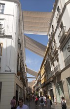 Fabric spread over buildings to provide shade in busy shopping street Mendez Nunez in central