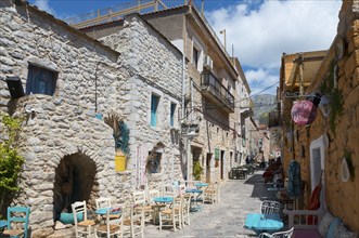 Cosy alley with stone houses and a alleyway café in a small Mediterranean town on a sunny day, Old