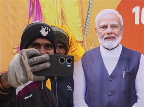 People takes selfie with a cutout poster of Indian Prime Minister Naredra Modi, on the eve