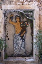 A mural of Bacchus surrounded by plants on an old stone wall, Umag, Istria, Croatia, Europe