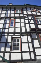 Facade of a half-timbered house with windows against a cloudless blue sky in the historic centre of