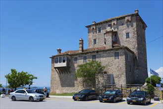 Byzantine defence defence tower under a clear blue sky, surrounded by cars and visitors,