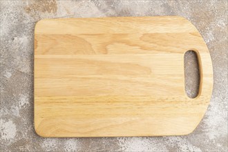 Empty rectangular wooden cutting board on brown concrete background. Top view, close up, flat lay