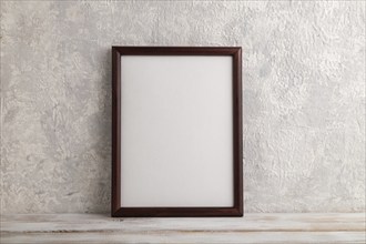 Brown wooden frame mockup on gray concrete background. Blank, vertical orientation, still life,