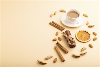 Composition with almonds, cinnamon and cup of coffee on orange pastel background. Blank, side view,