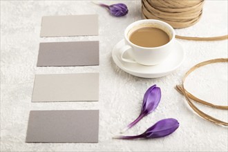 Gray paper business card mockup with spring snowdrop crocus flowers and cup of coffee on gray