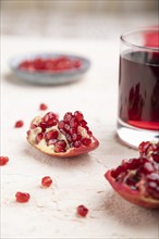 Glass of pomegranate juice on a white concrete background with red textile. Side view, close up,