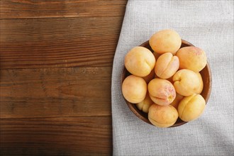 Fresh orange apricots in wooden bowl on wooden background. top view, flat lay, copy space