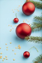 Christmas or New Year composition. Decorations, red balls, fir and spruce branches, on a blue paper