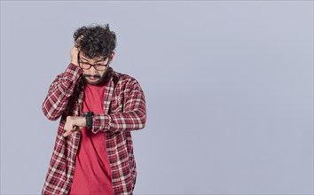 Worried young man looking at his watch isolated. Worried person looking at his watch isolated