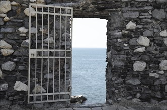 Stone Wall with Open Gate Door with Mediterranean Sea View in a Sunny Day in Liguria, Italy, Europe