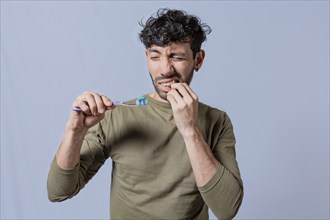 Young man holding toothbrush with gum pain. Man holding toothbrush with gum pain, People holding