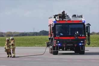 Firefighters from the airport fire brigade stand next to a Ziegler F95 fire engine at BER Airport