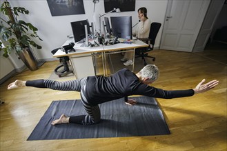 Symbolic photo on the subject of occupational health management. A woman exercises on a sports mat