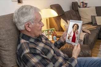 Symbolic image of telemedicine, elderly patient speaking to a doctor in a video conference from