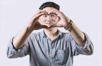 Handsome young man making heart shape with hands isolated. Smiling latin man making heart shape