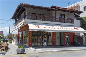 A shop for orthodox products on a sunny street with customers in front, Ouranoupoli, City of