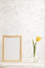 Wooden frame with orange tulip flower in glass on gray concrete background. side view, copy space,