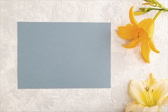 Blue paper business card mockup with orange day-lily flower on gray concrete background. Blank, top