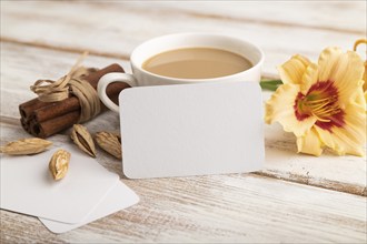 White paper business card mockup with orange day-lily flower and cup of coffee on white wooden