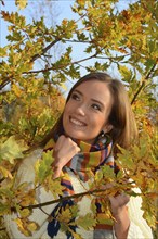 Portrait of young beautiful smiling woman, 30 years old, outdoors in forest with autumn colors in