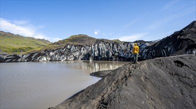 Tourist on the shore of a glacier lagoon, glacier tongue and lake, Sólheimajökull, South Iceland,