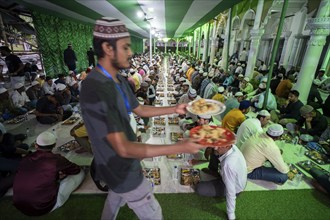 Volunteers distribute and arrange rows of 'iftar' meal for devotees to break their fast, during the