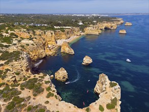 Aerial view of a rugged coastal landscape with rocky islands and boats in turquoise water, beach,