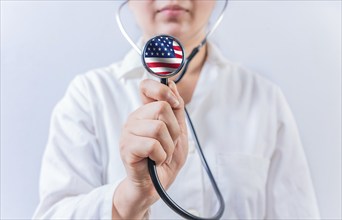 Female doctor holding stethoscope with USA flag. USA Health and Care concept