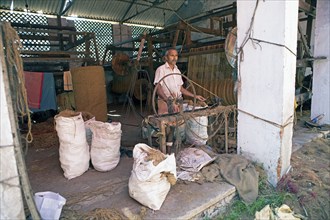 Indian worker winding coils in the Labourers Coir Mats and Mattings Cooperation, coir mat