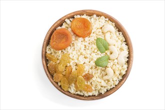 Bulgur porridge with dried apricots, raisins and cashew in wooden bowl isolated on white background