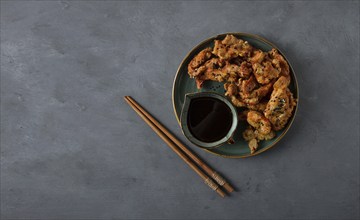 Fried meat in batter, deep-fried, with sesame seeds, and soy sauce, on a gray table, there are no