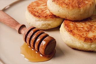 Cottage cheese pancakes, with honey, close-up, on a beige table, selective focus, no people