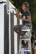 Indian artist painting a wall during the international contemporary art exhibition Kochi-Muziris