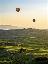 Hot air balloon drifting above undulating tuscan hills in sunsets golden light, AI generated