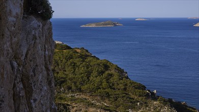 View of the sea with distant islands and a rocky, overgrown coast, Makri Island, Alimia Island,