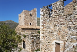 Two stone buildings of a historic village structure under a clear sky, residential towers, Vathia,