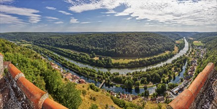 Panoramic view of a winding river surrounded by forests and hills, in the foreground a village and