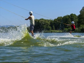 Children wakeboard across the lake, water sports, water skiing and wake park