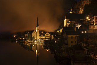 View of Hallstatt with the church and Lake Hallstatt at night. Clouds move through Hallstatt.