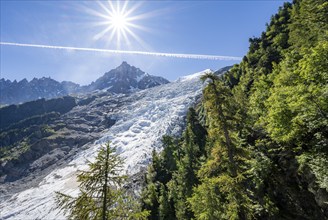 View of glacier Glacier des Bossons with sun star, behind summit of Aiguille du Midi, Chamonix,