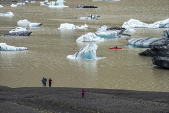 Single kayaker in red kayak, glacial lake at the glacier solheimajökull, icebergs on the lake,