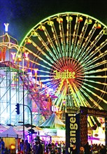 Cranger Kirmes with colourfully illuminated fairground rides and the Ferris wheel at night, Herne,