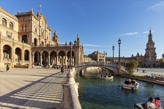 People enjoying boat rides on the water next to a curved bridge under the sun, Seville