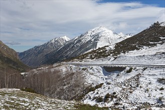 Berglandschaft mit Resten von Schnee am Straßenrand und bewölktem Himmel, nördlich von El Pas de la