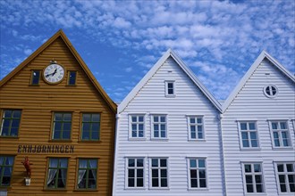 Traditional wooden houses under a blue sky with pitched roofs and multiple windows in a sunny old