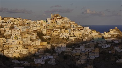 Town in the warm light of the morning sun on a hill with sea view, Colourful mountain village,